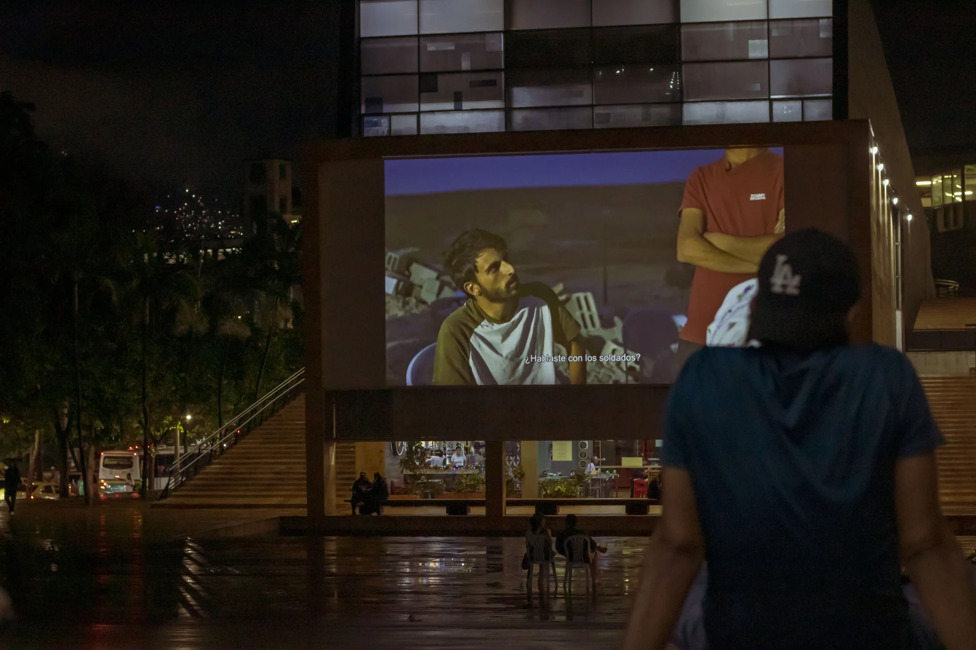 Una proyección de cine al aire libre entre los árboles y los edificios del barrio