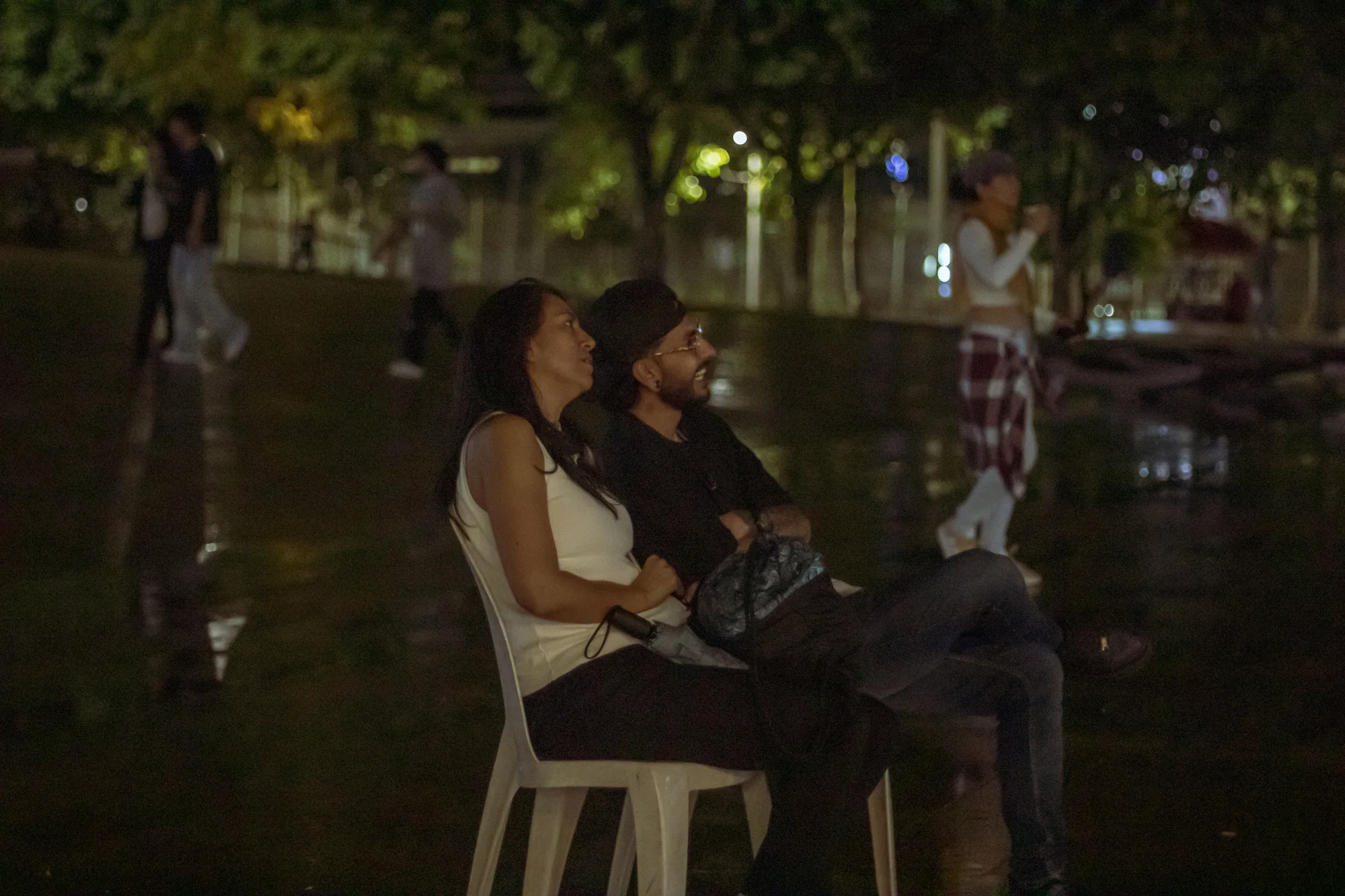 Dos personas entre el público de una proyección al aire libre.